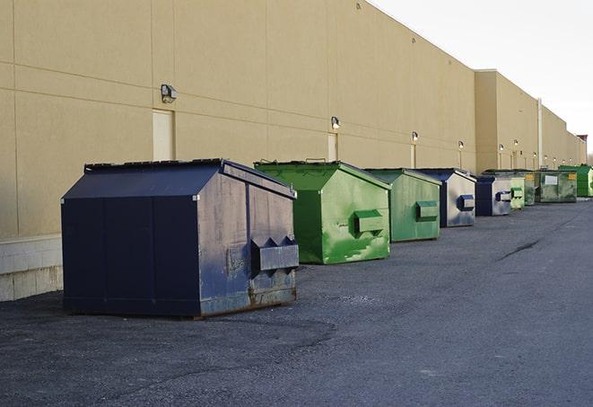 construction workers throw waste into a dumpster behind a building in Canton